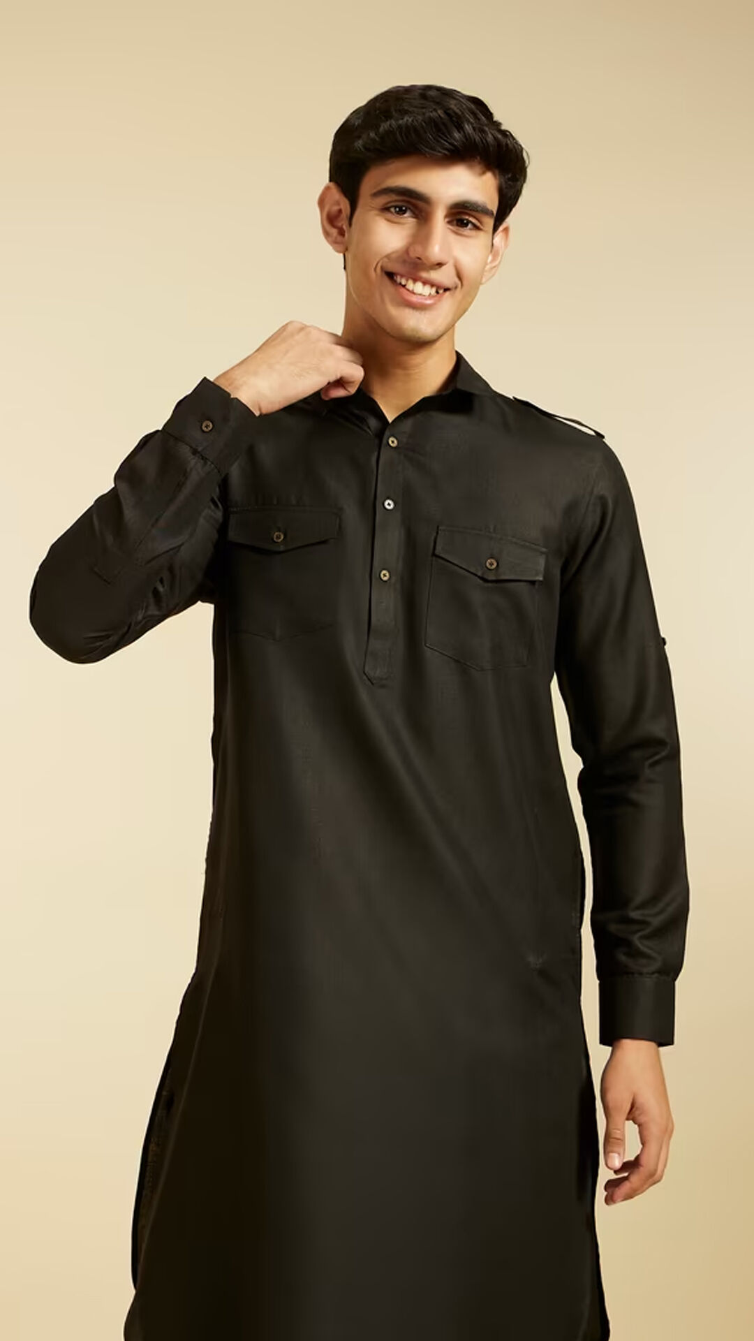 Man in elegant black embroidered kurta standing in a bright white luxury room, showcasing monochrome ethnic fashion style